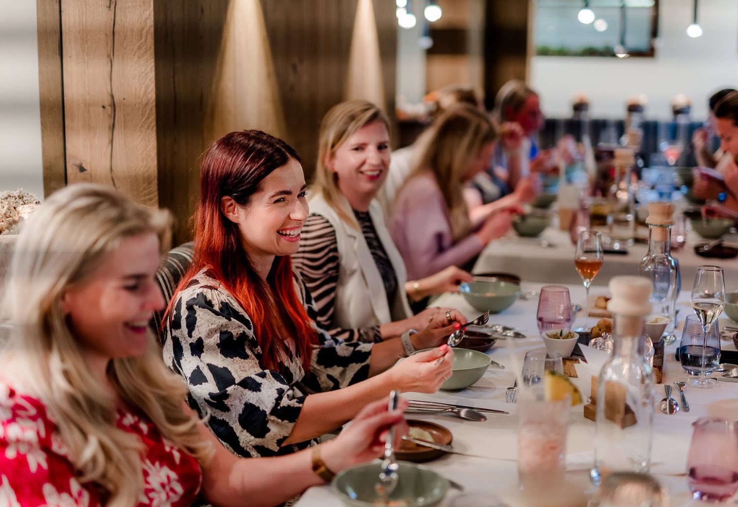 De groep lacht aan de lange tafel tijdens het diner