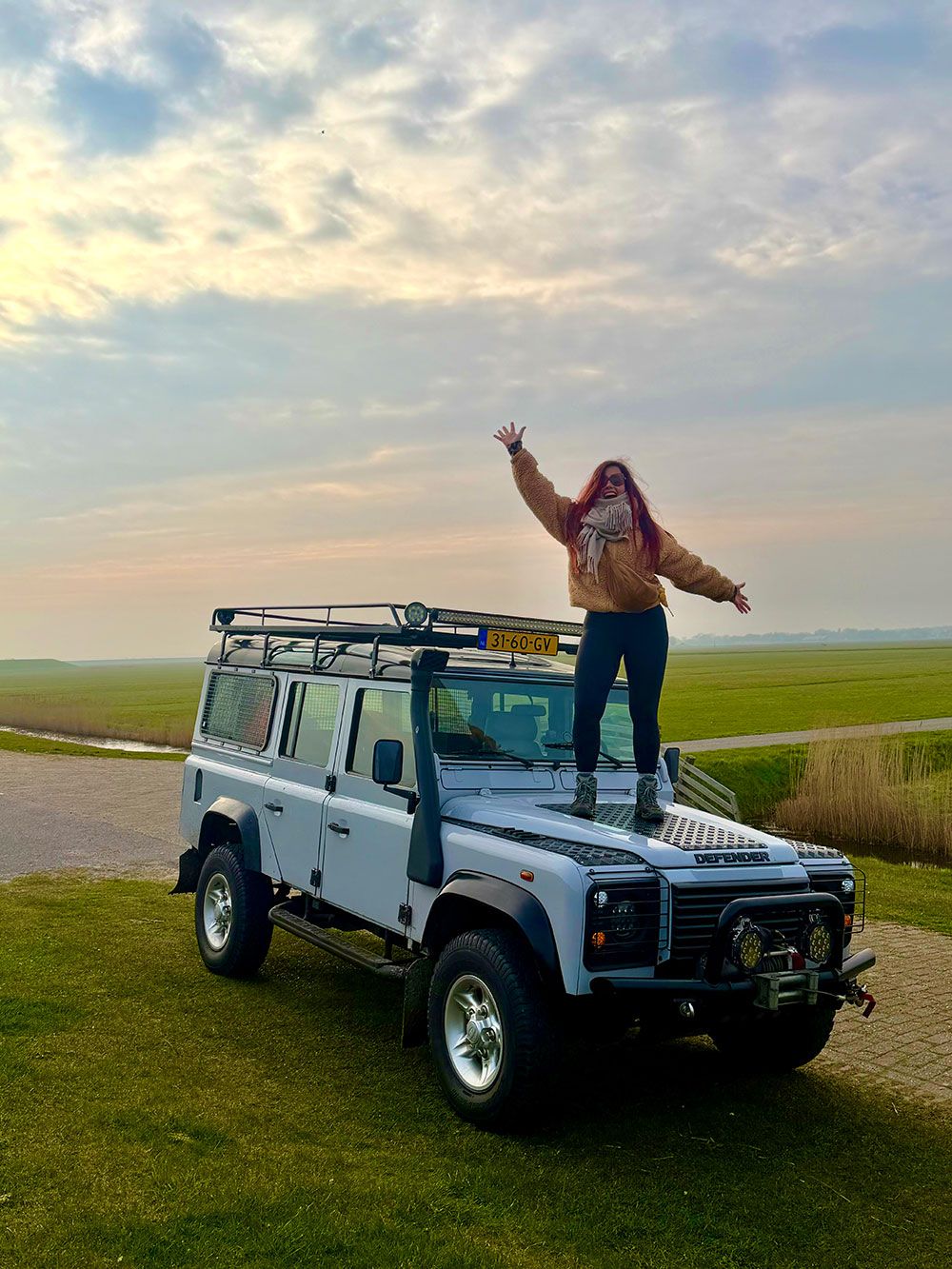De Land Rover op de dijk bij zonsondergang